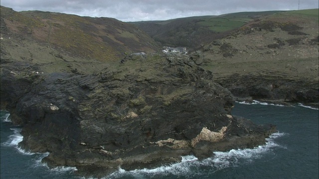 空中的岩石悬崖俯瞰着被起伏的绿色山丘包围的海洋/Boscastle，康沃尔，英格兰视频素材