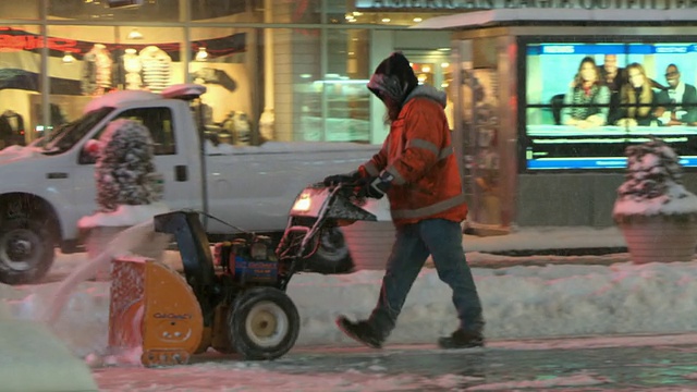 一名交通部官员在暴风雪中推着吹雪机穿过时代广场视频素材