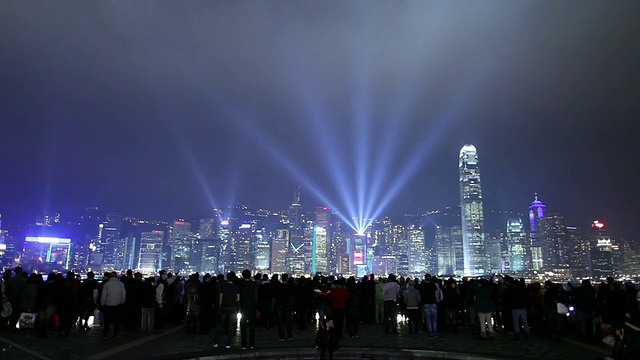 中国香港，人们在晚上看着维多利亚港上空灯火通明的城市天际线视频素材