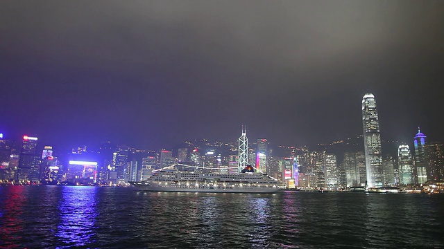 晚上穿过维多利亚港的WS城市天际线，游船穿过海港/中国香港视频素材