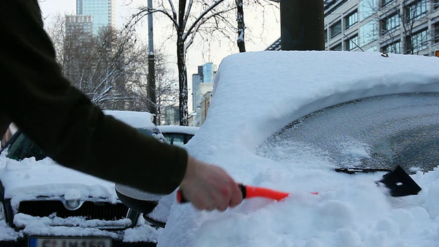 汽车上覆盖着雪，用刮冰器把它刮掉视频素材