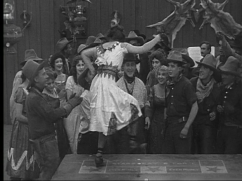 1915年B/W宽镜头女人在酒吧里一群牛仔面前在桌子上跳舞视频素材