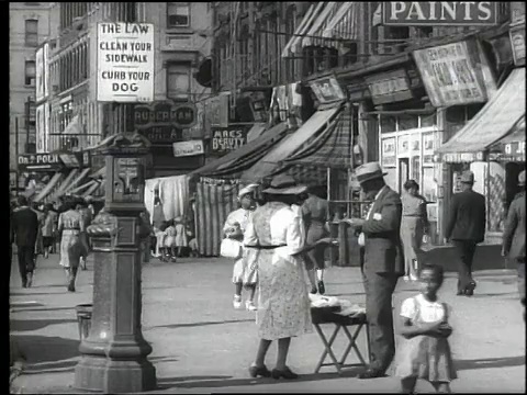 1939年，B/W公共汽车+商店门面在西130行人，遮阳篷/哈莱姆海鲜标志/妇女在街上卖衣服，妇女和儿童卖冰/纽约市视频素材