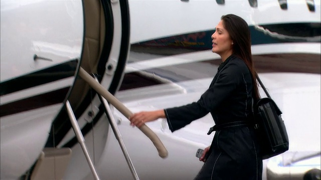 在美国佛罗里达州迈阿密的洛卡机场(Opa Locka Airport)，中景女商人走向私人飞机并挥手致意视频素材