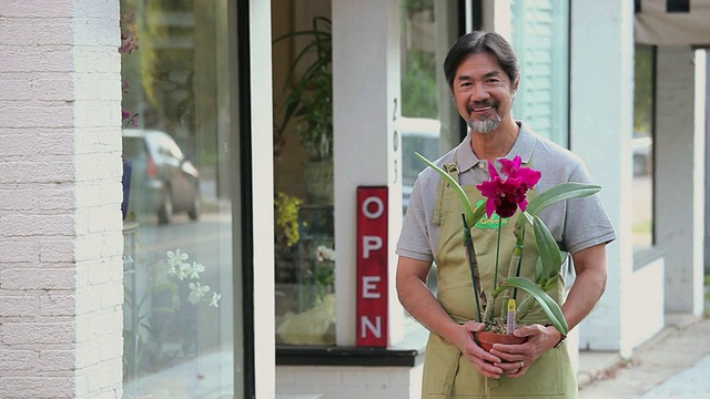 美国弗吉尼亚州里士满花店前，花商手持盆兰的肖像视频素材