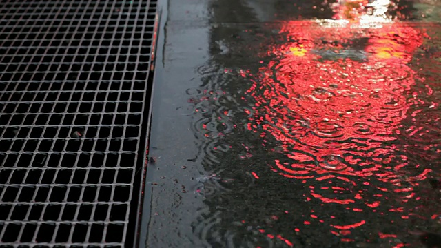 雨水洒在人行道上，折射着霓虹灯视频下载