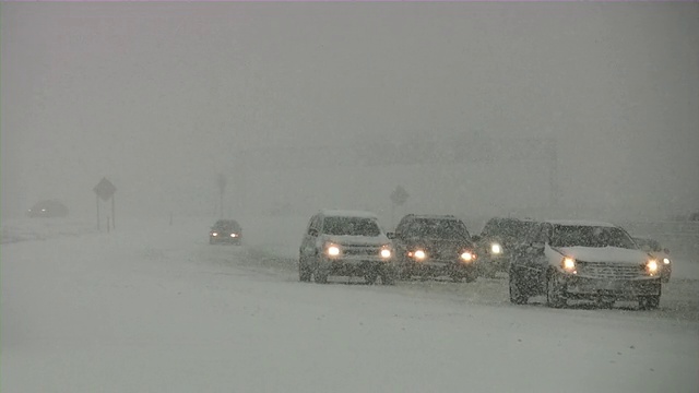 暴风雪。冬季交通。汽车在滑溜溜的路上行驶。下雪,雪花。视频素材