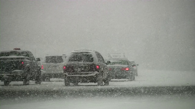 暴风雪。冬季交通。汽车在滑溜溜的路上行驶。下雪,雪花。视频素材