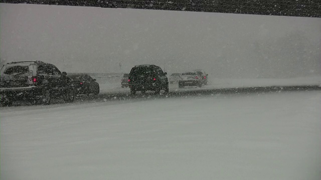 暴风雪。冬季交通。汽车在滑溜溜的路上行驶。下雪,雪花。视频素材