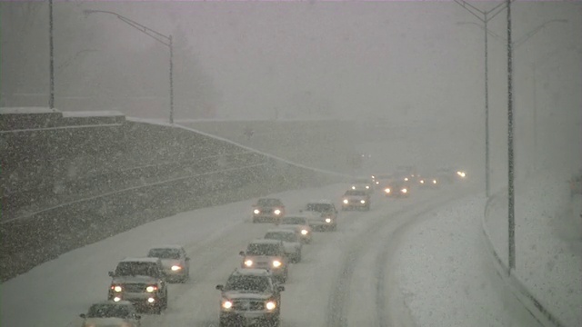 暴风雪。冬季交通。汽车在滑溜溜的路上行驶。下雪,雪花。视频素材