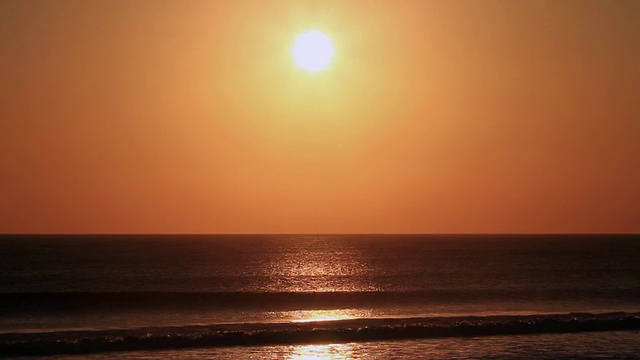 太阳落在巨浪冲击海滩的剪影后面/ Legian，巴厘岛，印度尼西亚视频素材