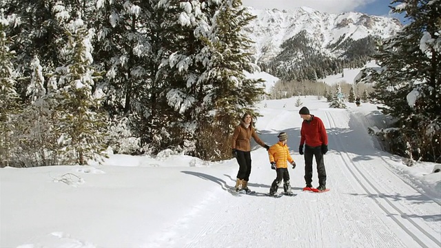 冬天的一天，父亲穿着雪鞋跑回家，在美国爱达荷州的太阳谷玩耍视频素材