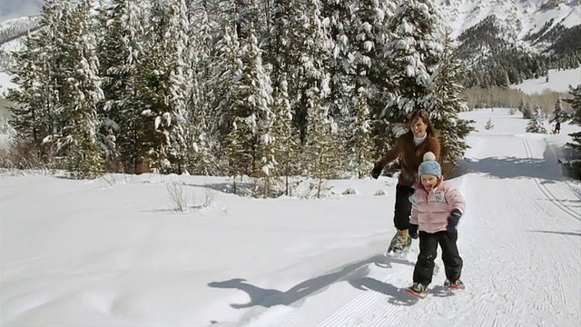 WS POV母亲和年幼的女儿赛车和玩雪鞋/太阳谷，爱达荷州，美国视频素材