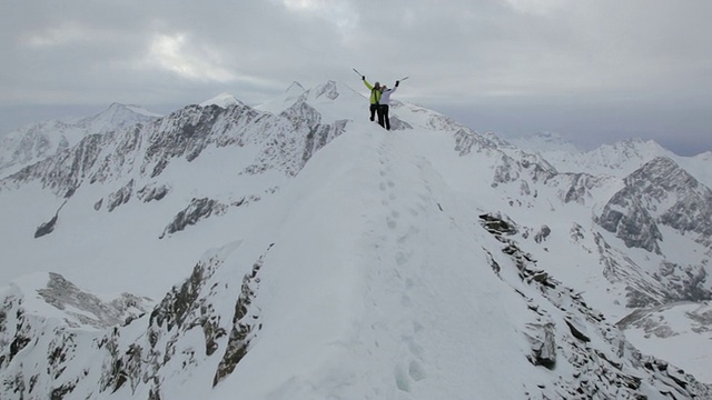 一对登山爱好者在奥地利阿尔卑斯山脉附近的白雪覆盖的山上，一名男子正在帮助一名女子/奥地利泰洛斯图拜冰川视频素材