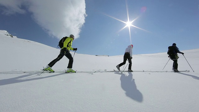 在早晨的阳光下，三名登山者在奥地利阿尔卑斯山的冰雪覆盖的山上徒步旅行/奥地利泰罗尔的斯图拜冰川视频素材