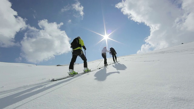 在早晨的阳光下，三名登山者在奥地利阿尔卑斯山的冰雪覆盖的山上徒步旅行/奥地利泰罗尔的斯图拜冰川视频素材