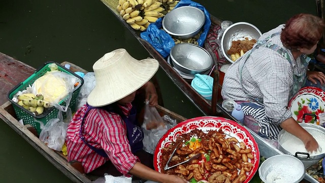 泰国曼谷，Ratchaburi Provinvr，在Damnoen Saduak水上市场，一名女士在出售船上的美味食物视频素材