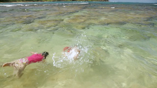 男孩和女孩一起浮潜在浅海/夏威夷考艾岛莫洛阿海滩，美国视频素材