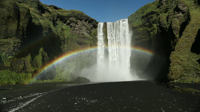 MS Rainbow over luch Skogafoss waterfall，黑色火山沙环绕区域/ HOF, Vestur-Skaftafellssysla，冰岛视频素材