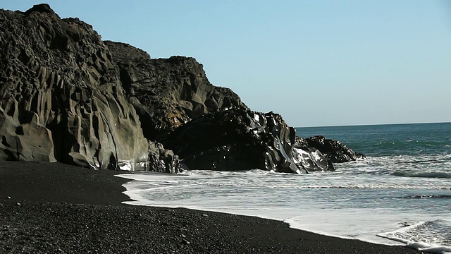 黑色岩层环绕着黑色岩石海滩，海浪冲击着海岸/ VIK, Vestur-Skaftafellssysla，冰岛视频素材