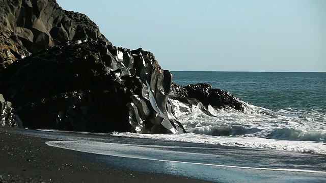 黑色岩层环绕着黑色岩石海滩，海浪冲击着海岸/ VIK, Vestur-Skaftafellssysla，冰岛视频素材