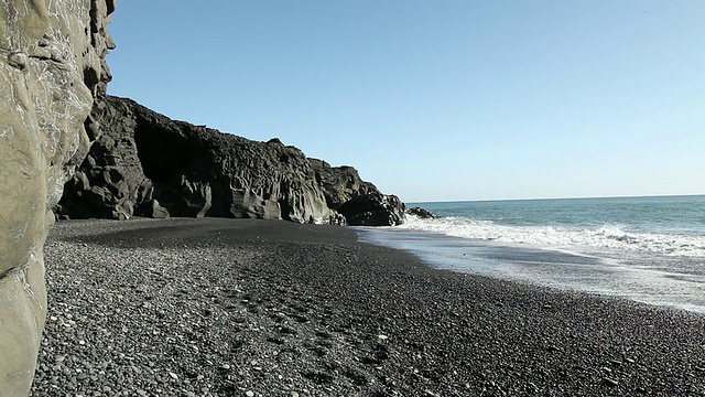 黑色岩层环绕着黑色岩石海滩，海浪拍打着海岸/ VIK, Vestur-Skaftafellssysla，冰岛视频素材