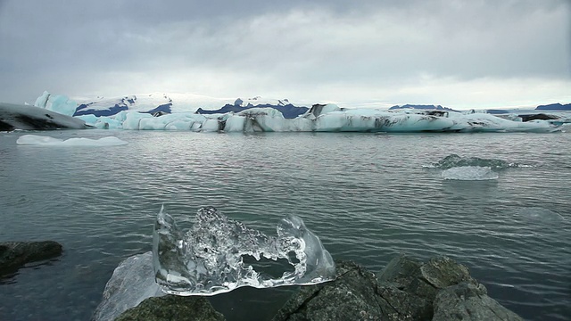 小块冰坐在Jokulsarlon冰川泻湖前的岩石上，冰块融化和下落/在Skaftafell国家公园和Hofn之间，austurskaftafellssysla，冰岛视频素材