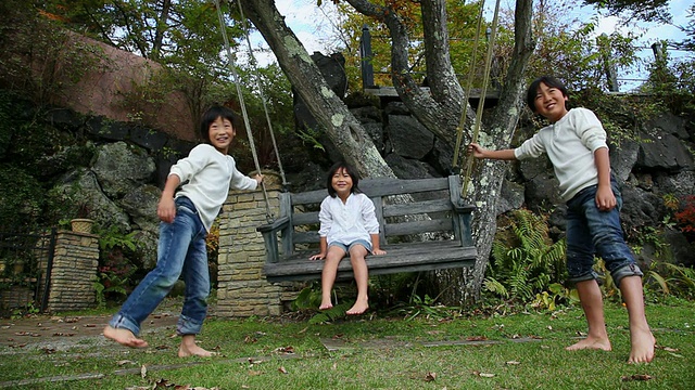 女孩坐在秋千上，孩子们在推秋千/藤川口子，山梨县，日本视频素材