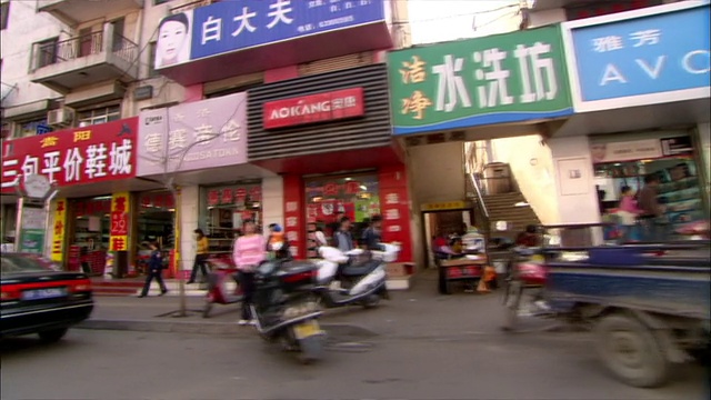 POV -在一个中国城市的街道上开车，有很多的店面和彩色的标志和海报/中国视频素材