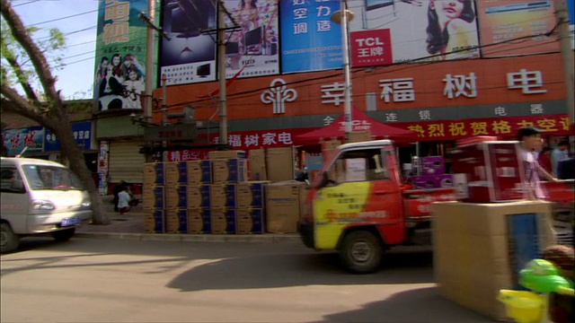 POV -在一个中国城市的街道上开车，那里有许多店面和彩色的招牌和海报/中国视频素材