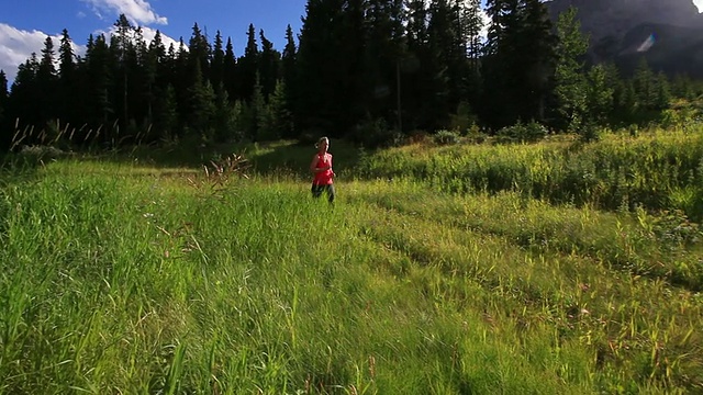 女人在阳光下跑过高山草地视频素材