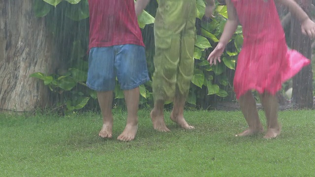 三个孩子在雨中玩耍视频素材