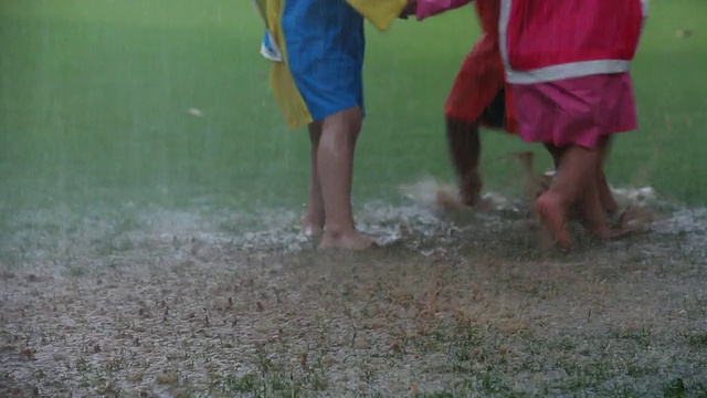 三个孩子在雨中玩耍视频素材