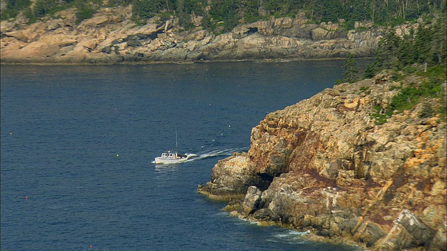 航拍，沿岩石海岸线/沙漠山岛航行的船，缅因州视频素材