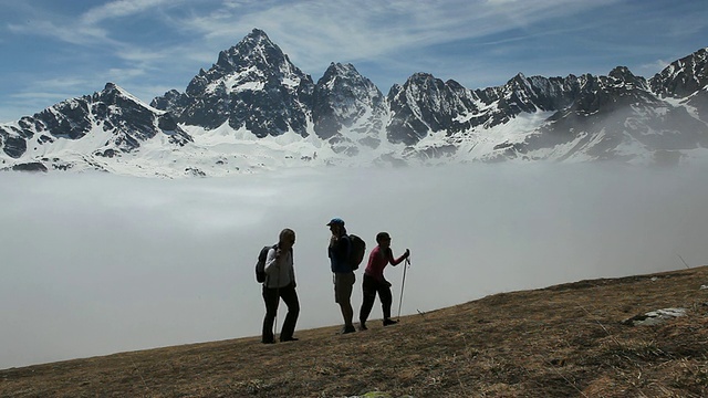 女徒步旅行者爬上了雾大雪山之上的草地视频素材