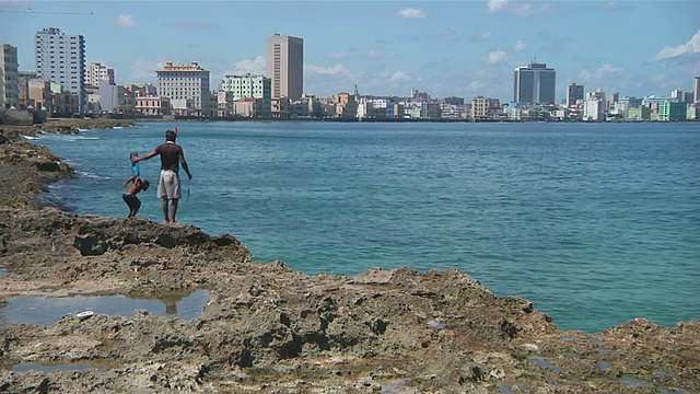 WS男孩跳进水和老哈瓦那天际线背景/哈瓦那，哈瓦那，古巴视频素材