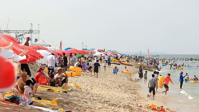 在韩国江原道江陵的京浦台海滩上，人们在帐篷和遮阳板上放松视频素材