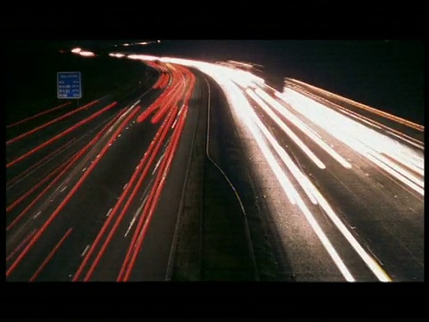 高角度，夜间在繁忙的高速公路上有条纹的车辆进出摄像头(行驶在路的左侧)视频素材