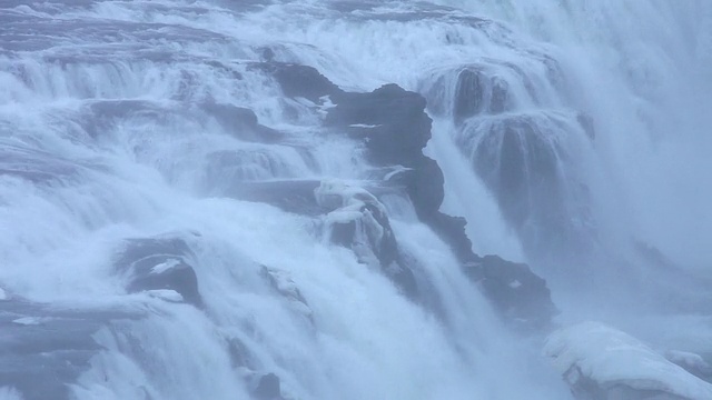 冰岛的瀑布被雪覆盖，瀑布上落下的水形成雾和水花视频素材