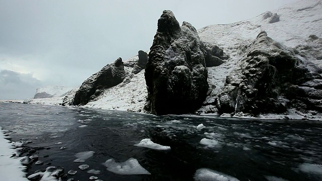 水和冰雪在冰雪覆盖的悬崖/冰岛前沿着河流而下视频素材