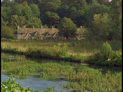 乡村别墅，阿灵顿街，Bibury -经典的英国别墅，乡村建筑，科林河在前景，水植物视频素材