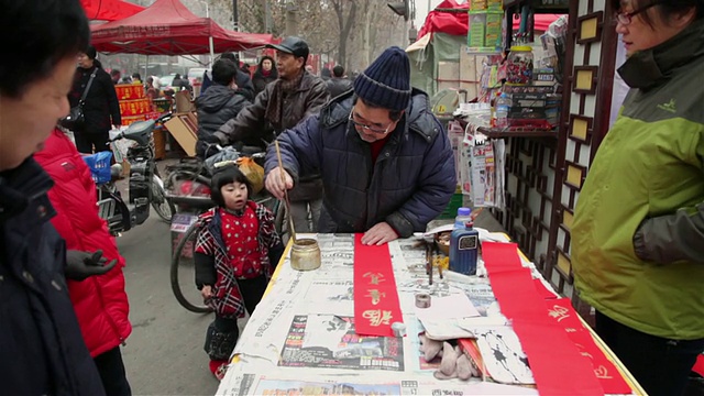 中国陕西西安，一个中国人在街道市场写春联视频素材