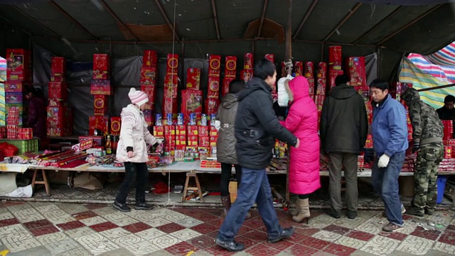 中国陕西西安，大雪纷飞的春节期间，人们在街头市场购买烟花和鞭炮视频素材