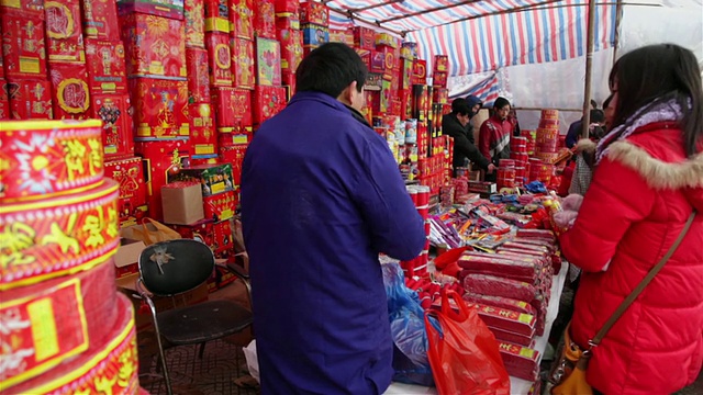 中国陕西西安，春节期间，人们在街头市场购买烟花和鞭炮视频素材