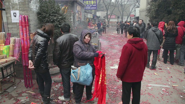 中国农历新年期间，中国陕西西安，一名女子在寺庙前出售红经幡视频素材