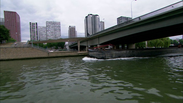 中等右跟踪-一艘驳船从巴黎的一座桥下滑出。法国/巴黎视频素材