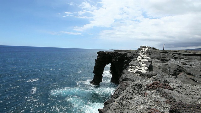 在阳光明媚的一天，美国夏威夷大岛的火山国家公园，海浪再次撞击霍莱海拱视频素材