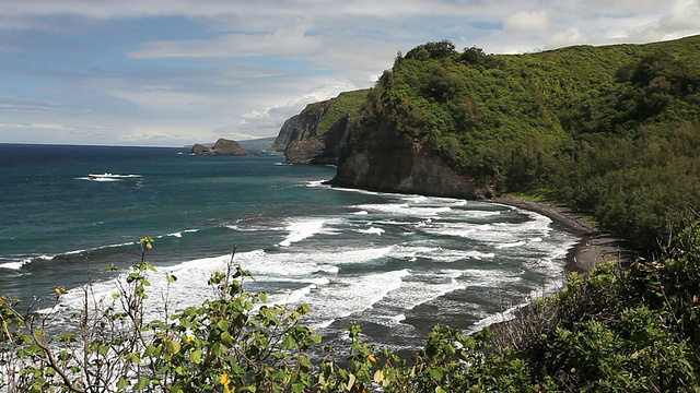 Pololu Valley cliffs with ocean waves on Pololu Valley beach seen through灌木丛/ Waimea，夏威夷，大岛，美国视频素材