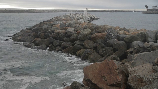 宽镜头的弯曲岩石墙与海浪撞击它。视频素材