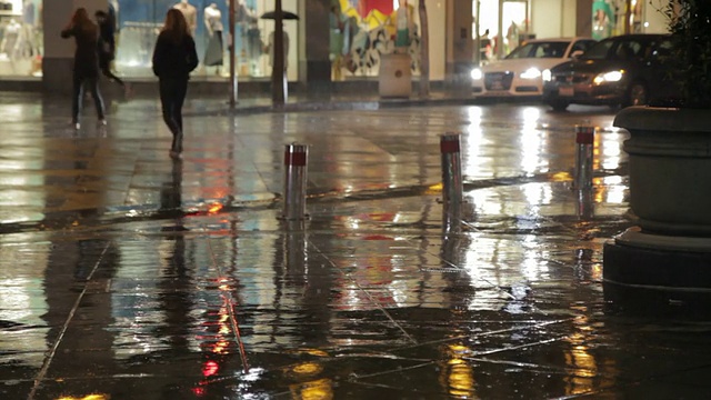 人们在雨中行走和奔跑在夜晚的街道上视频素材